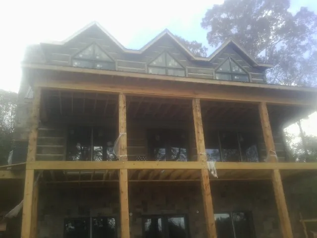 Dormers and porch framing on a large log home under construction — Roof Coating work by our crew in Rogers