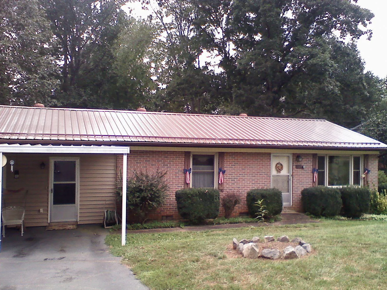 Bronze metal roof and carport on a brick ranch home — Roof Repair work by our crew in Rogers